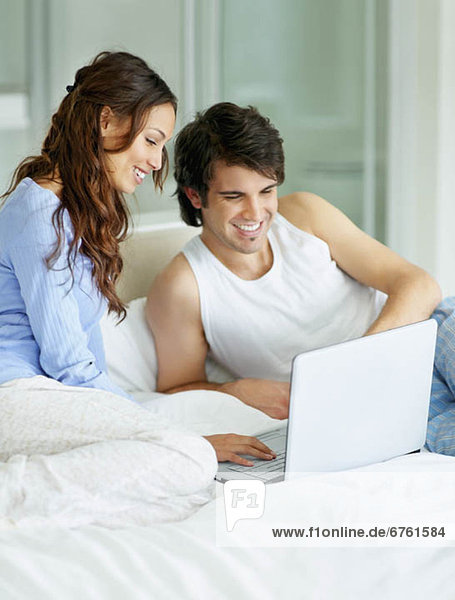 South Africa  Young couple using laptop while sitting on bed