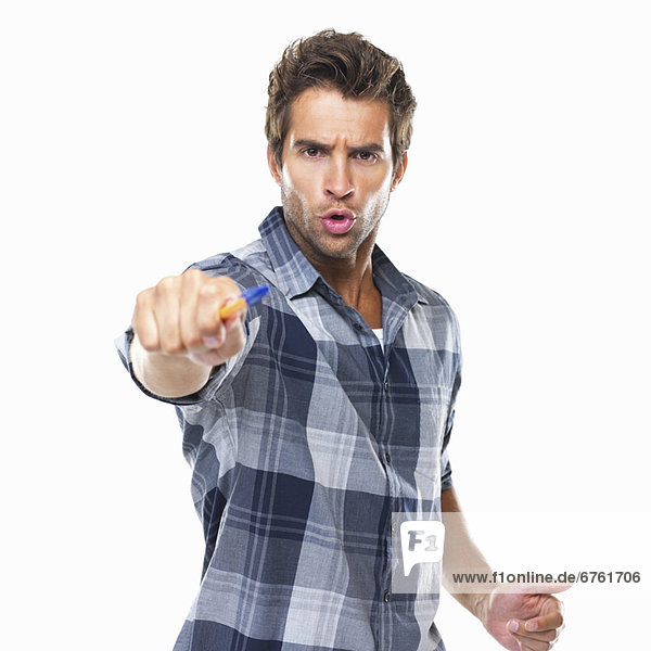 Studio shot of young confident man pointing with pen at camera