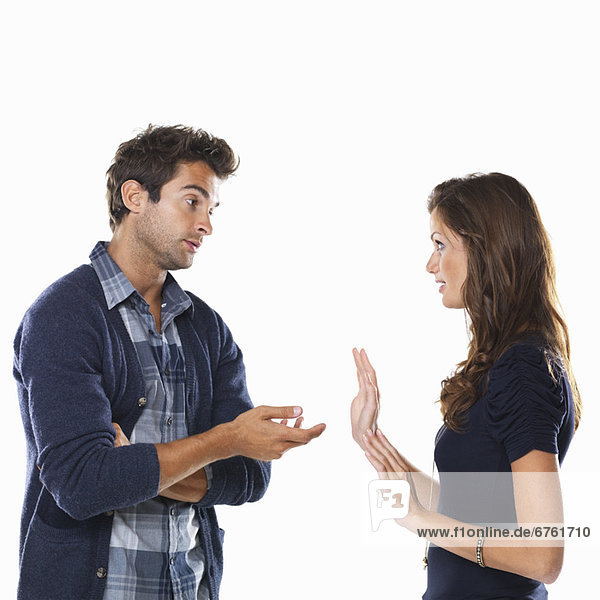 Studio shot of young couple having argument and gesturing