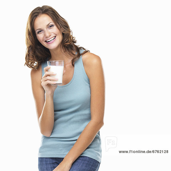 Studio portrait of attractive young woman smiling and holding glass of milk