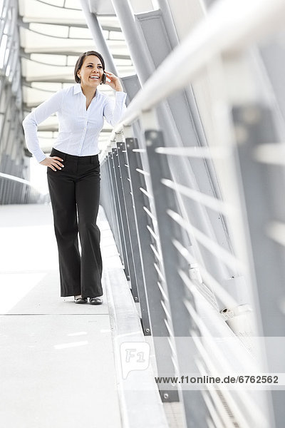 Young businesswoman on walkway  using cell phone