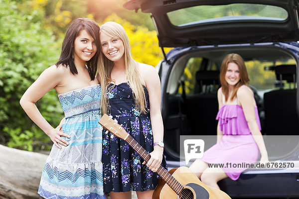 Portrait of young women with guitar by car