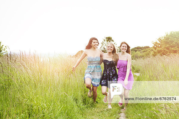 Three young women running in meadow