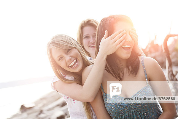 Three young women hanging out  covering eyes and laughing