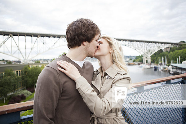 Young couple kissing on bridge