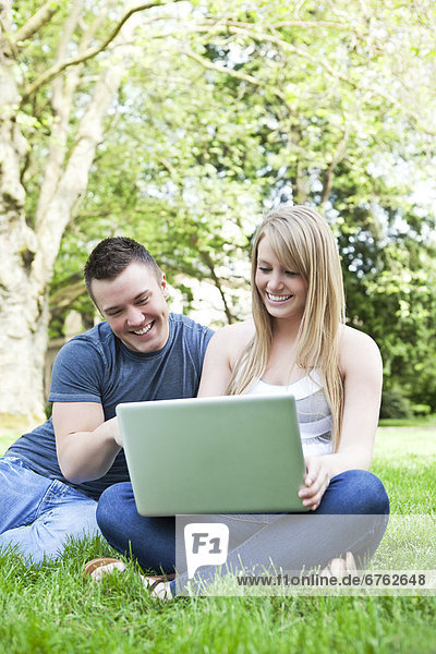 Couple using laptop in park