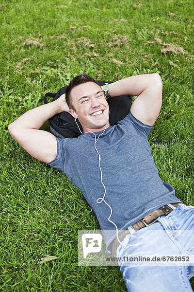 Man lying on grass listening to mp3 player