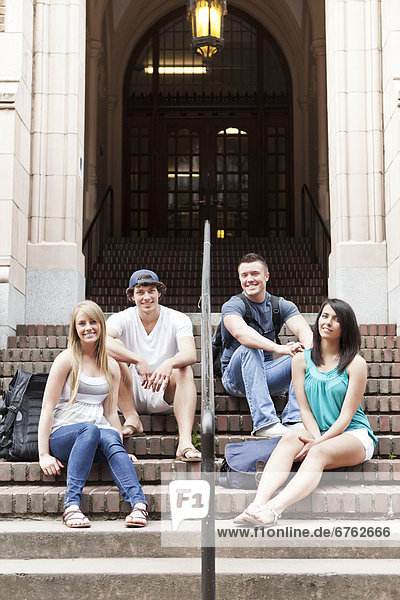 Portrait of four college students sitting on steps