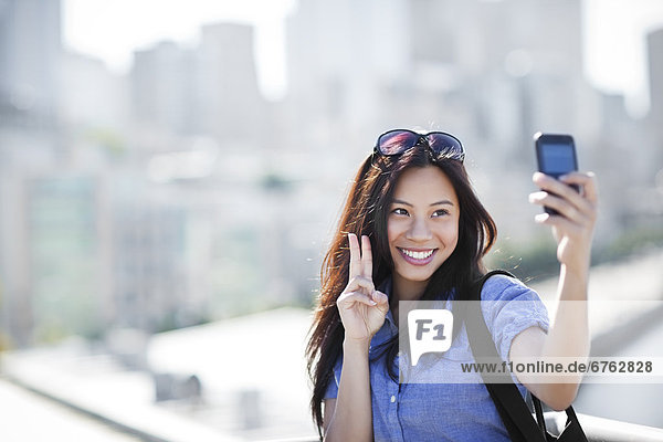 USA  Washington  Seattle  Woman photographing herself with smart phone outdoors