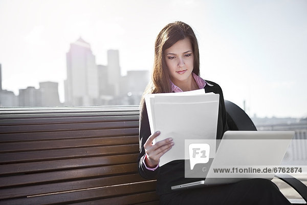 USA  Seattle  Young businesswoman sitting on bench and working