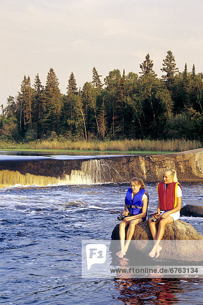 Teenage Girls sitting on a Rock in Lifejackets Fishing  Rainbow Falls  Whiteshell Provincial Park  Manitoba