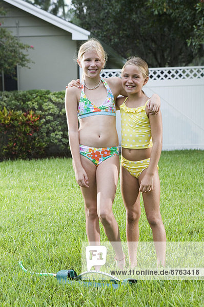 Girls playing with sprinkler in backyard