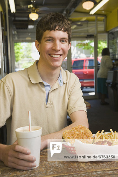 Teenage boy eating at fast food restaurant