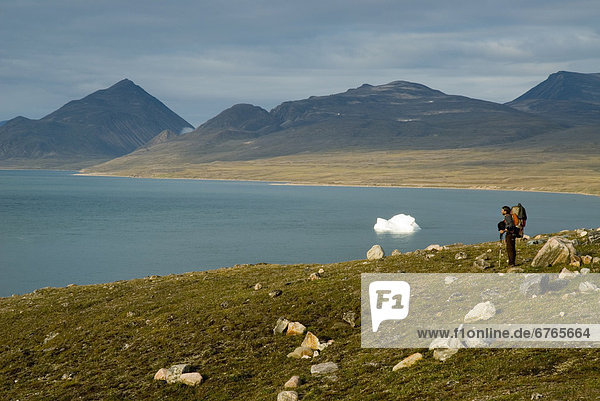 Man in arctic landscape with iceberg in background  Baffin Island  Nunavut  Canada