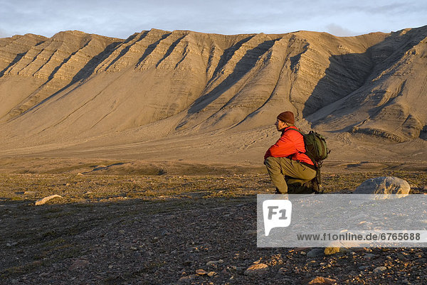 Man kneeling at Tay Bay  Bylot Island  Sirmilik National Park  Nunavut  Canada