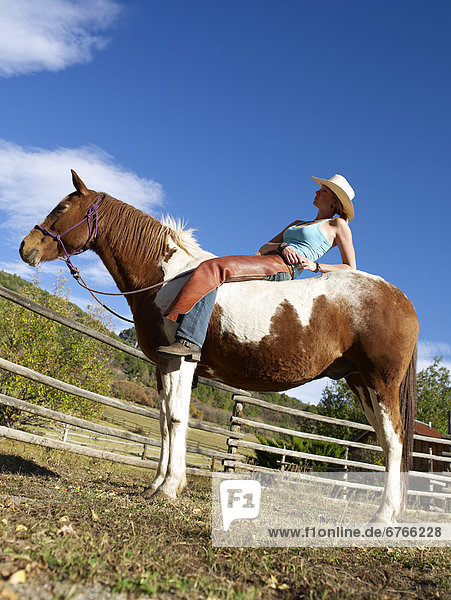 USA  Colorado  Cowgirl relaxing with horse on ranch