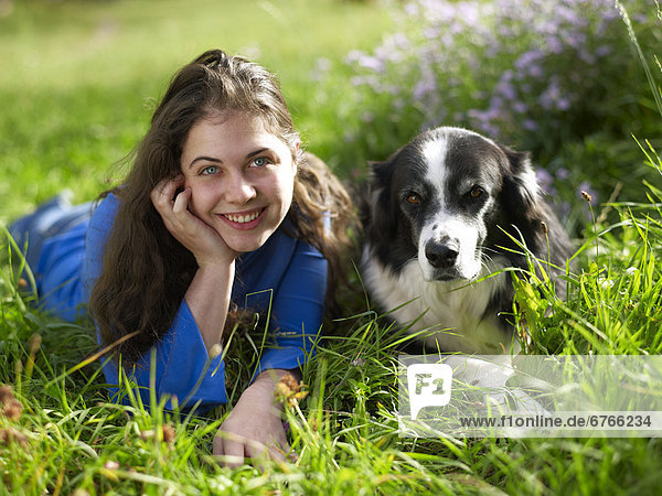 USA  Colorado  Portrait of young woman relaxing with dog on grass