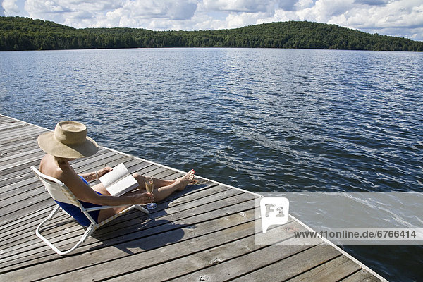 Woman reading on cottage dock  Smoke Lake  Algonquin Park  Ontario