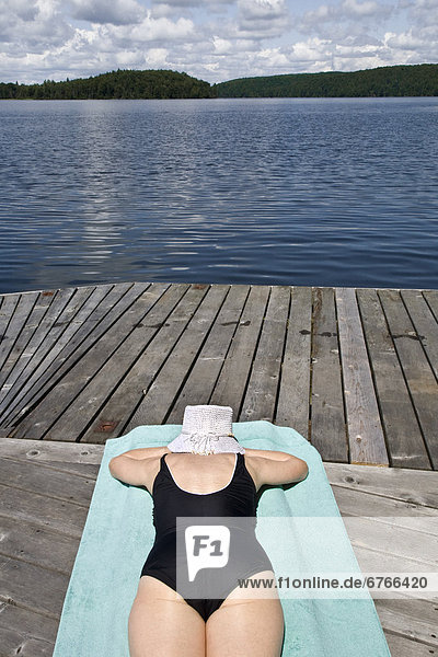 Woman sunbathing on cottage dock  Smoke Lake  Algonquin Park  Ontario