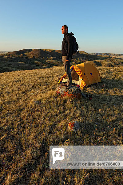 Man standing in front of tent at dawn  Tabletop Butte  Grasslands National Park  Saskatchewan