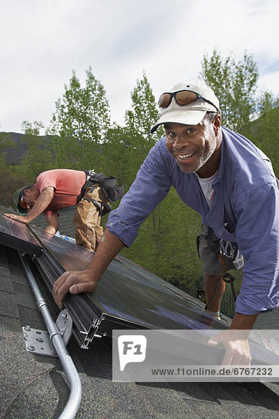 Construction workers installing solar panels on roof