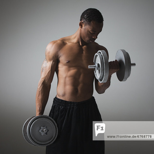 Muscular man lifting dumbbells