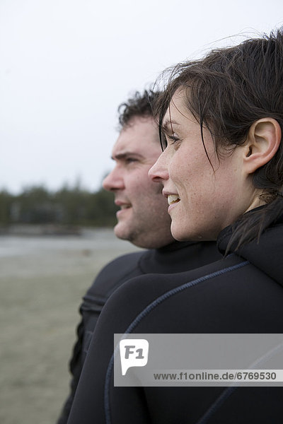 Man and Woman Surfers on Beach Looking towards Ocean  Tofino  British Columbia