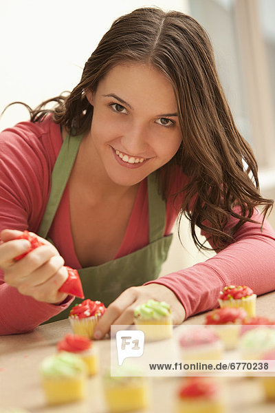 junge Frau junge Frauen Portrait Küche schmücken cupcake