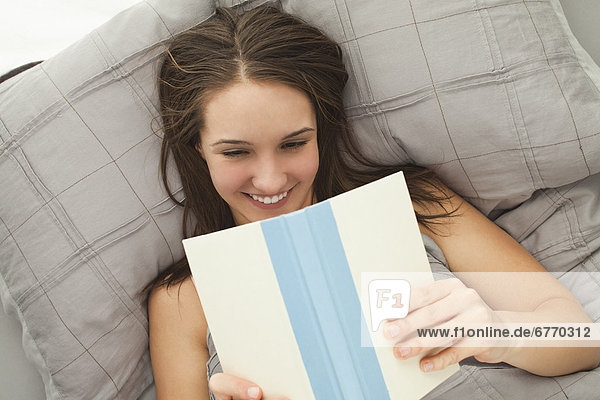 Junge Frau im Bett lesen