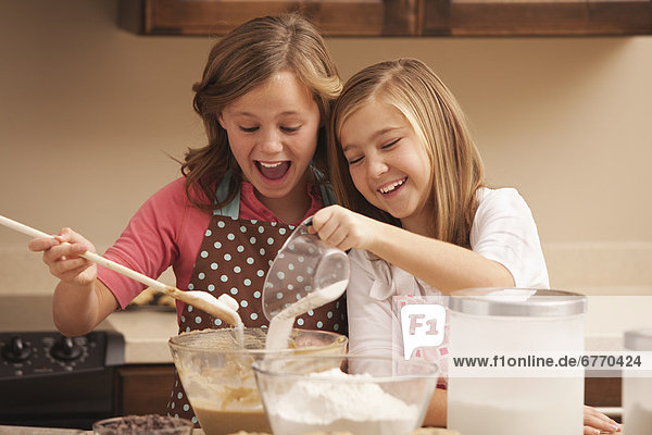 Two girls (10-11) baking in kitchen