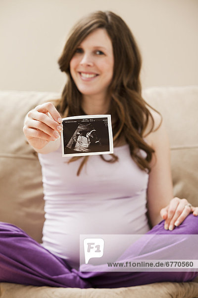 USA  Utah  Lehi  Young pregnant woman showing CT image of unborn baby
