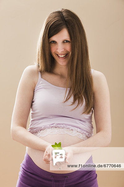 USA  Utah  Lehi  Young pregnant woman holding young plant