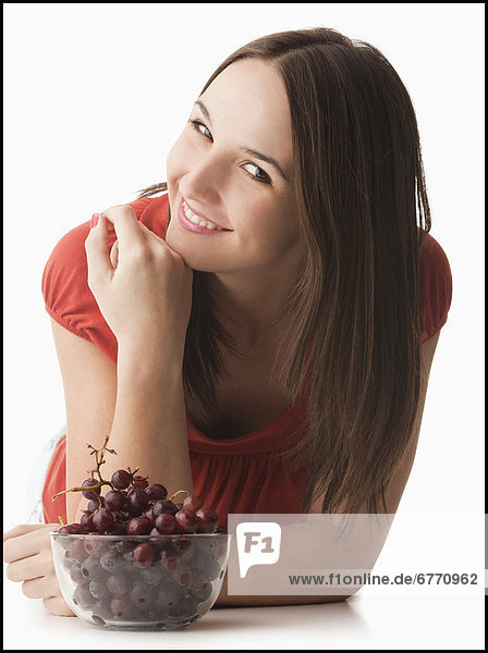 Studio portrait of young woman with grapes