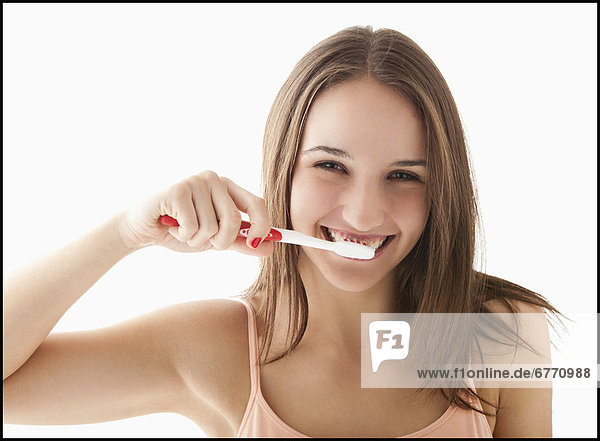 Studio portrait of young woman brushing teeth