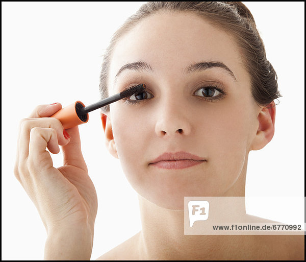 Studio portrait of young woman applying mascara