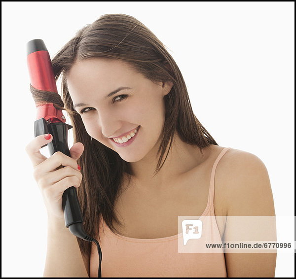 Studio portrait of young woman curling hair