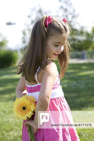 Little girl holding flowers behind her back  Queen Elizabeth Park  Vancouver  British Columbia