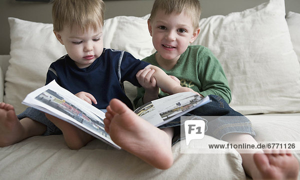 Toddlers reading a book on a sofa  Vancouver  British Columbia