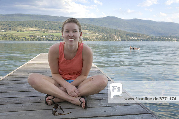 Young woman sitting on a dock  Okanagan Valley  British Columbia