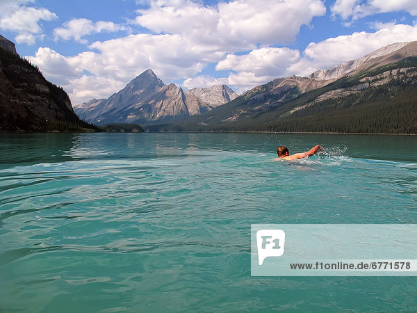Man swimming in Maligne Lake with Samson Peak in background  Jasper National Park  Alberta