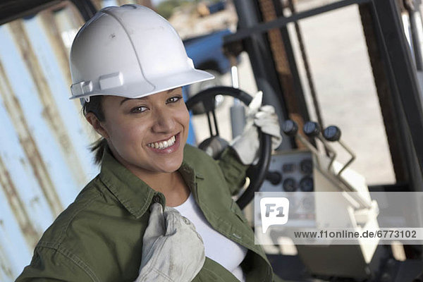 Portrait of female construction worker driving mechanical digger