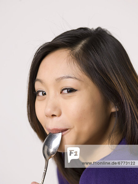 Young woman chewing spoon