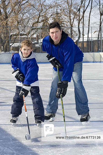 Father and son hockey players on an outdoor rink  Toronto  Ontario
