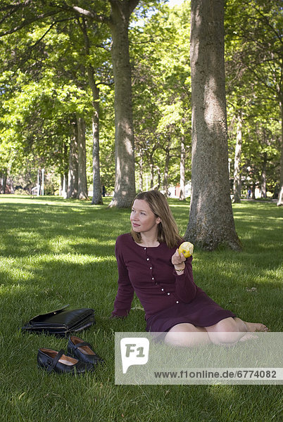 Woman sitting in a park with an apple  University of Victoria  Victoria  British Columbia