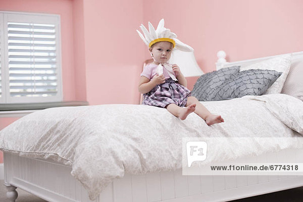 USA  Utah  small girl (2-3) with plume sitting on bed