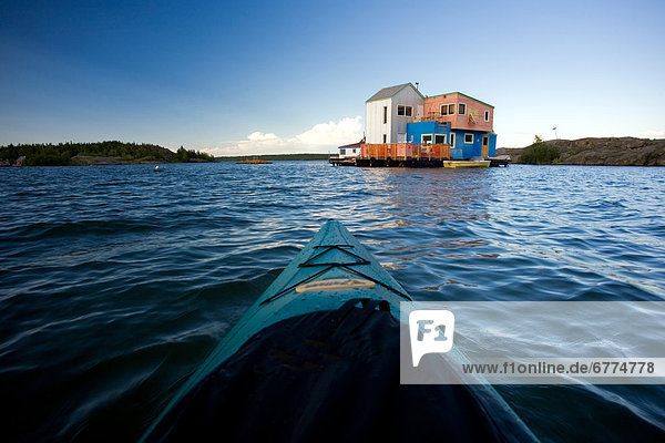 Kayaker approaching colourful houseboats  Yellowknife Bay on the Great Slave Lake  Yellowknife  Northwest Territories