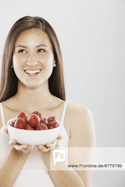 Brunette woman holding a bowl of strawberries
