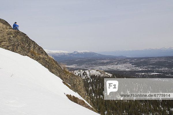 Hiker sitting on a Mountainside overlooking the Yukon River Valley from Fish Lake Trail  outside of Whitehorse  Yukon