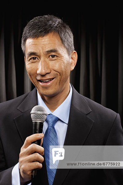 USA  Utah  Provo  Portrait of businessman with microphone standing in front of black curtain