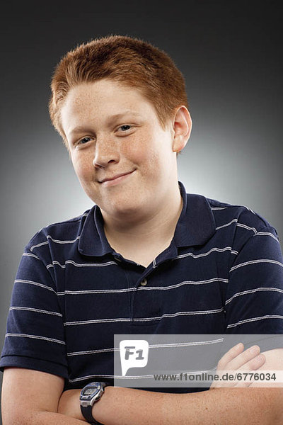 Portrait of redhead teenage boy (14-15) with arms crossed  studio shot